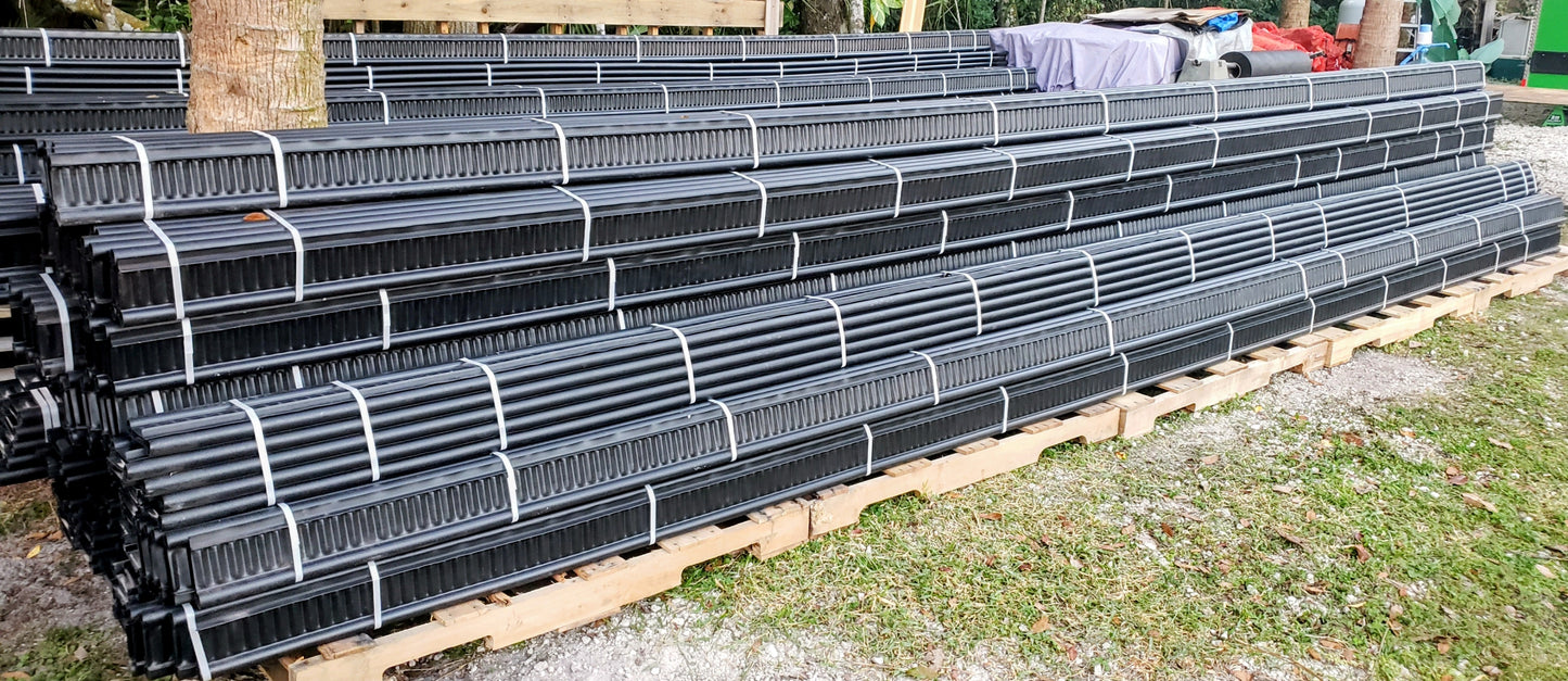 Stacks of Alpha Edge landscaping edging bundles on pallets at supplier yard, ready for bulk orders, for garden, pathway, and landscaping projects.