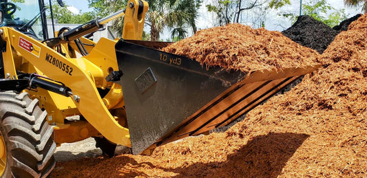 CAT loader with a full 1 cubic yard mulch bucket at a bulk landscape supply yard