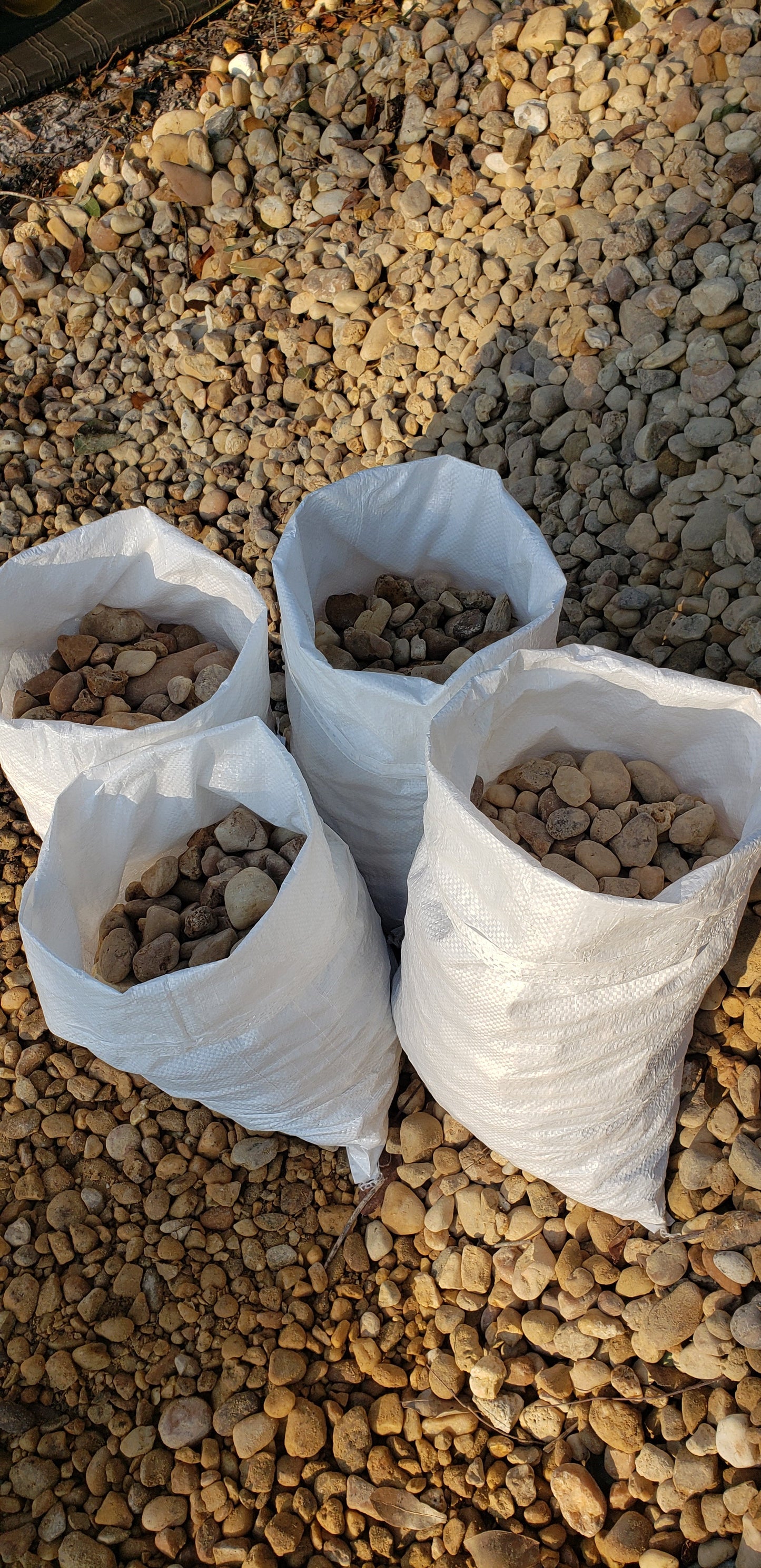 Bags of brown river rock 1 to 1.5 inch size neatly stacked for sale at Mulch and Stuff landscaping supply Ormond Beach