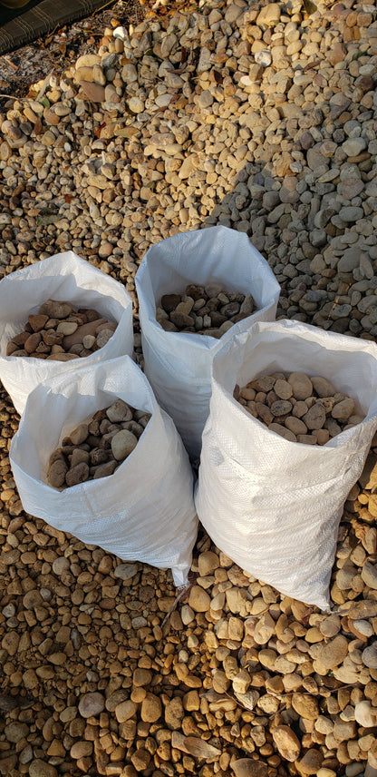 Bags of brown river rock 1 to 1.5 inch size neatly stacked for sale at Mulch and Stuff landscaping supply Ormond Beach